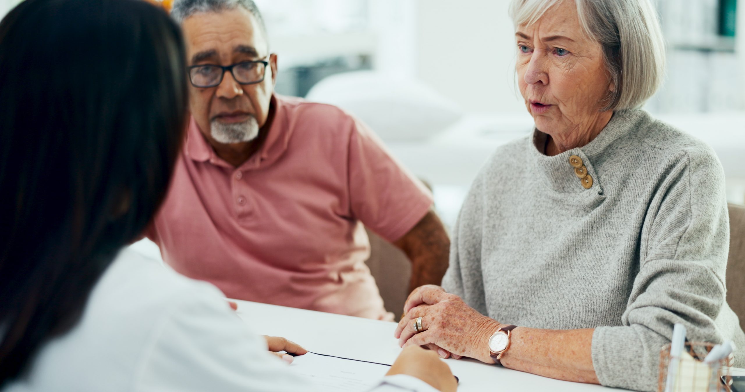 Doctor, consultation and discussion with elderly couple for hospice care. Medical employee, caregiver or nurse with senior patients for health prescription at clinic.