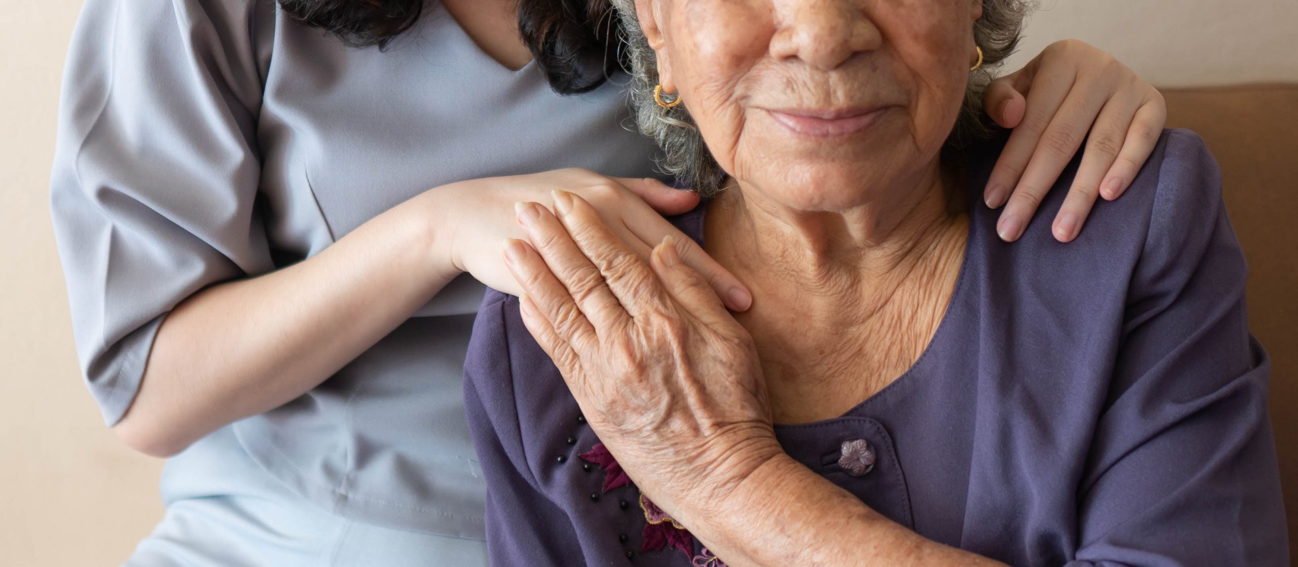 Friendly relationship between caregiver and happy eldery woman during nursing at home. Senior services and palliative care concept.